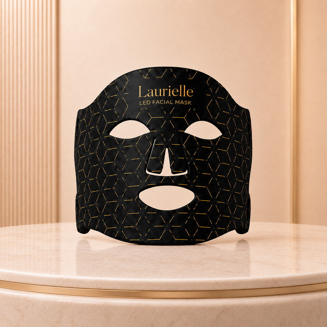 Black facial mask with gold geometric pattern on a beige surface, branded 'Laurielle'.