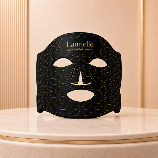 Black facial mask with gold geometric pattern on a beige surface, branded 'Laurielle'.